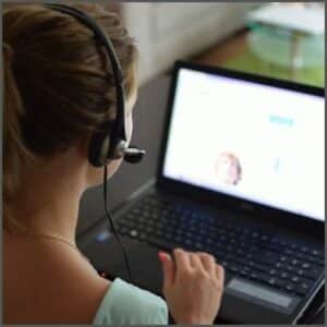 Bild einer Teilnehmerin mit Headset auf eine Laptop schauend während der Online Stottertherapie