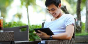 Ein Jugendlicher sitzt mit einem Tablet im Sessel und nimmt an der Online Therapie teil.