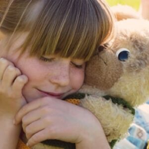 Ein kleines Mädchen kuschelt glücklich mit ihrem Teddy