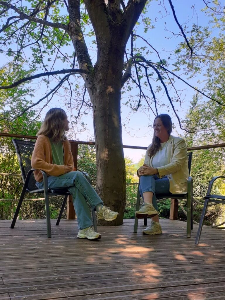 Zwei Therapeutinnen sitzen im grünen Therapieraum und unterhalten sich